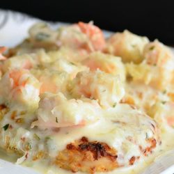 white decorative plate with oven fried chicken topped with creamy fontina shrimp sauce as viewed from above