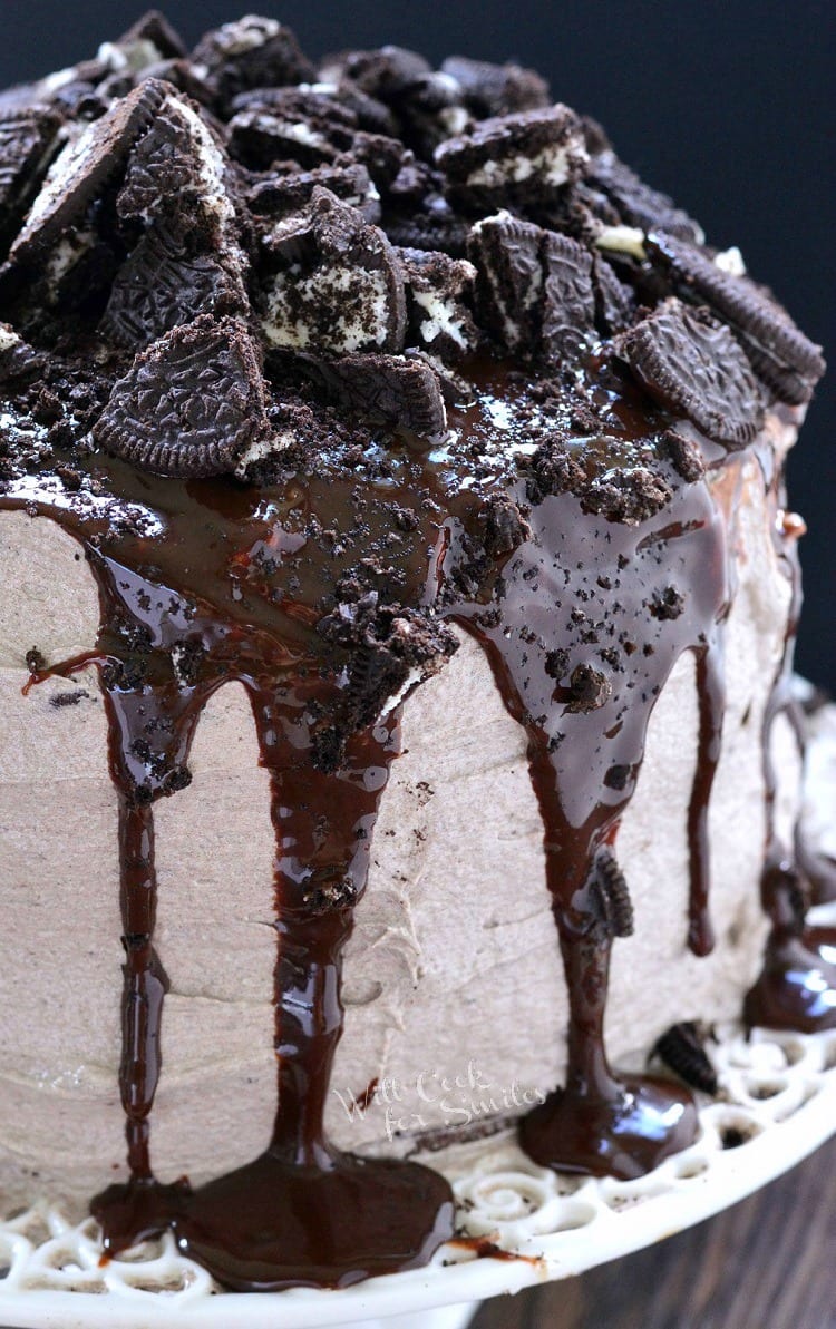 Chocolate oreo cake on a decorative cake presenter standing on a wooden table.