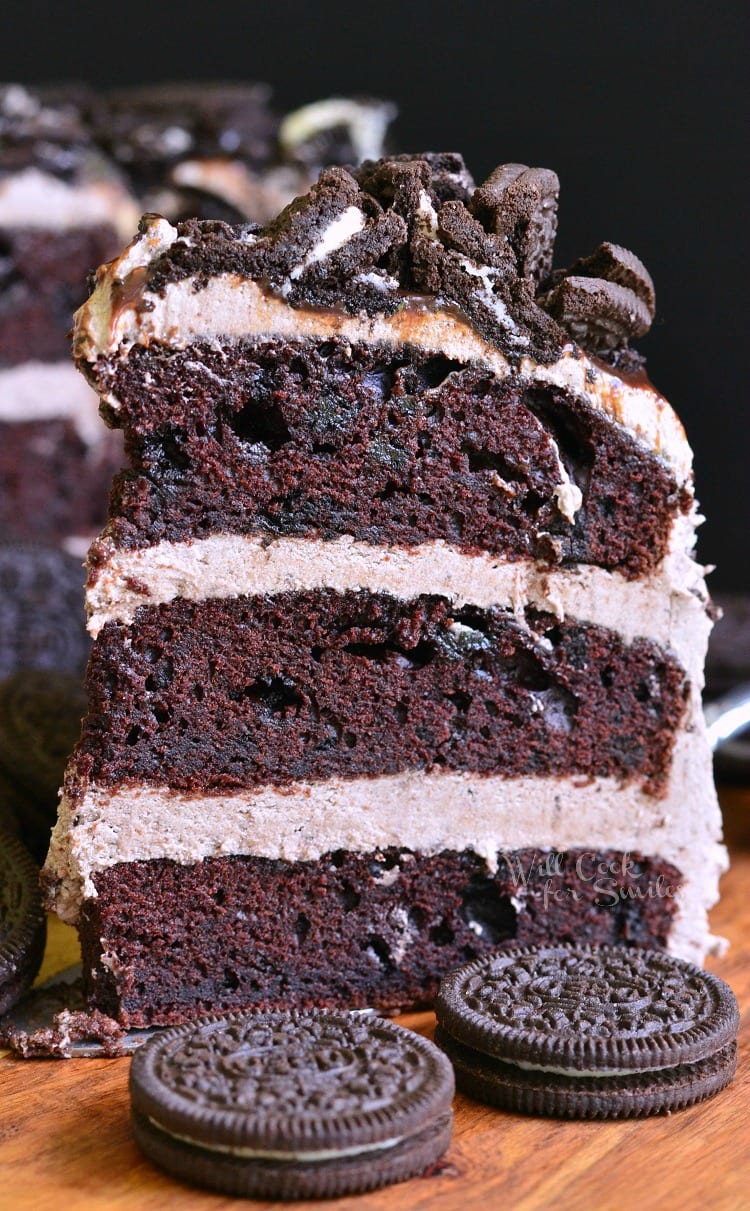 slice of Chocolate Oreo Cake on a cutting board with 2 oreos in front of it 