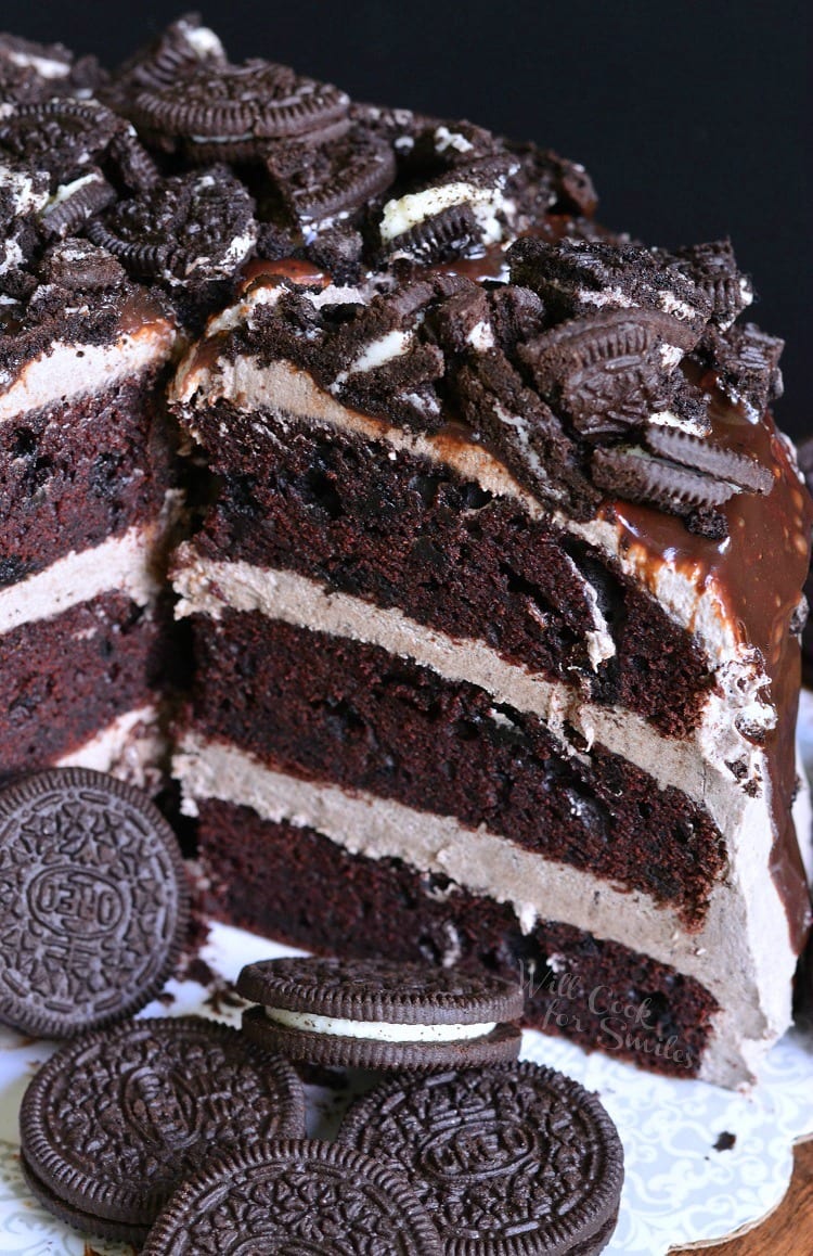 Chocolate Oreo Cake with cut up oreos and chocolate sauce on top of cake and oreos around the bottom on the plate