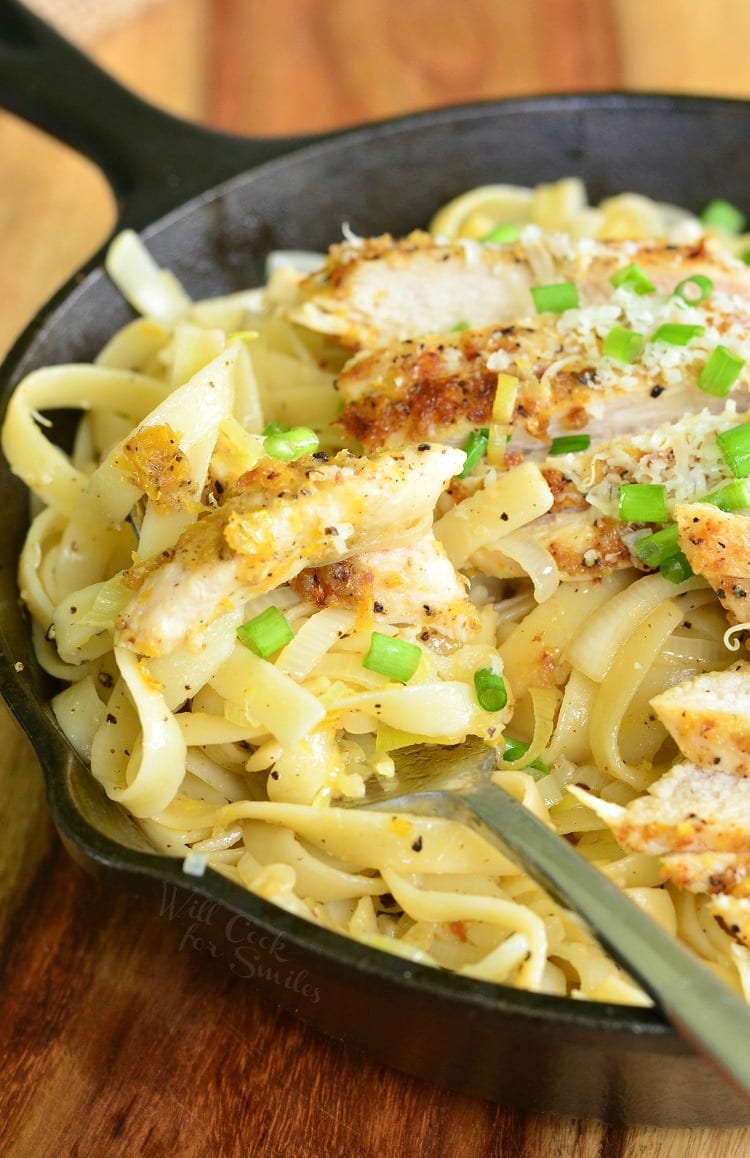 Lemon Pepper Chicken over Fettuccine in a cast iron skillet with green onions on top with a fork 