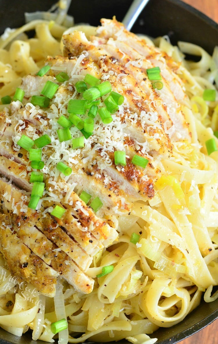 top view Lemon Pepper Chicken over Fettuccine in a cast iron skillet with green onions on top 