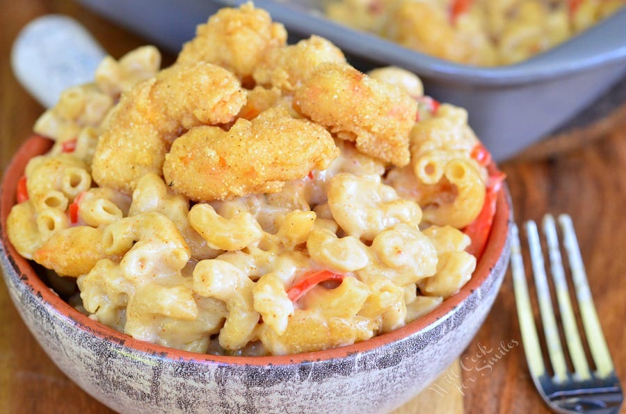 Po'Boy Mac and Cheese with fried shrimp on top in a bowl with a fork to the right 