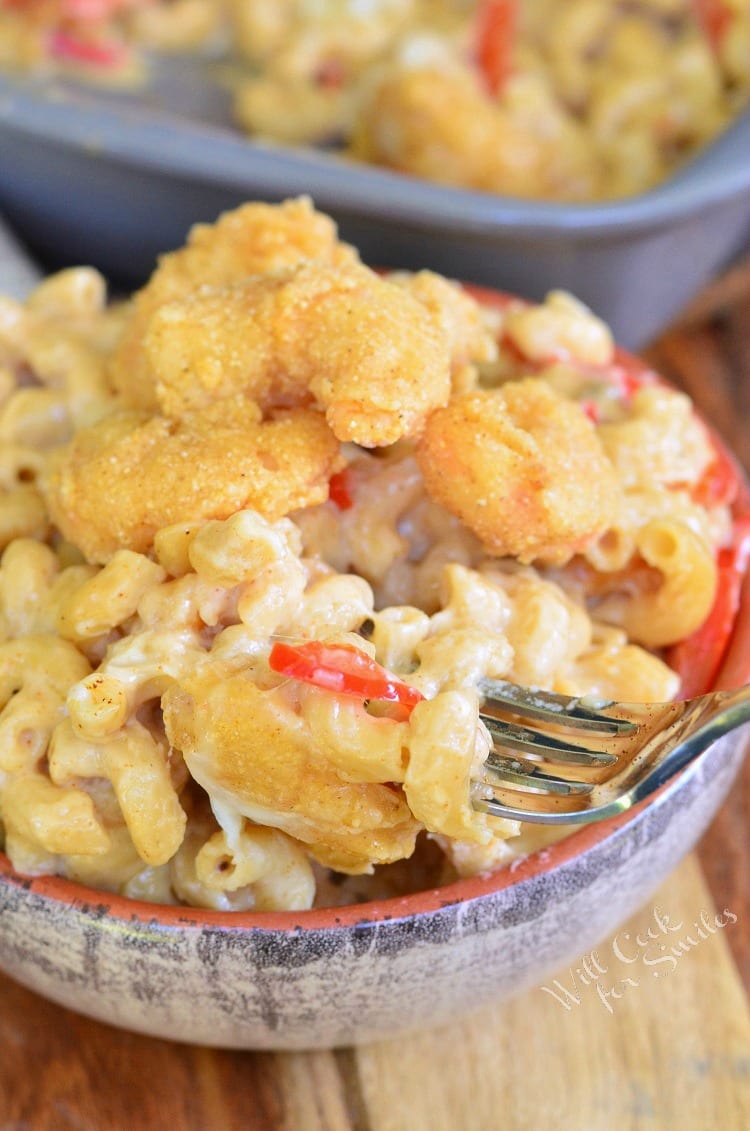 Po'Boy Mac and Cheese with fried shrimp on top in a bowl with a fork 