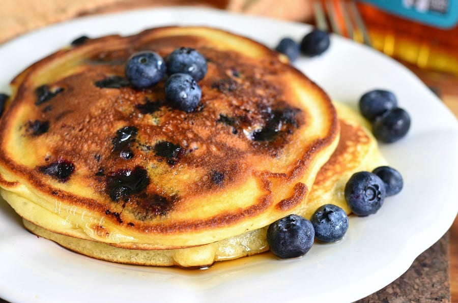 pancakes on the plate topped with fresh blueberries and syrup