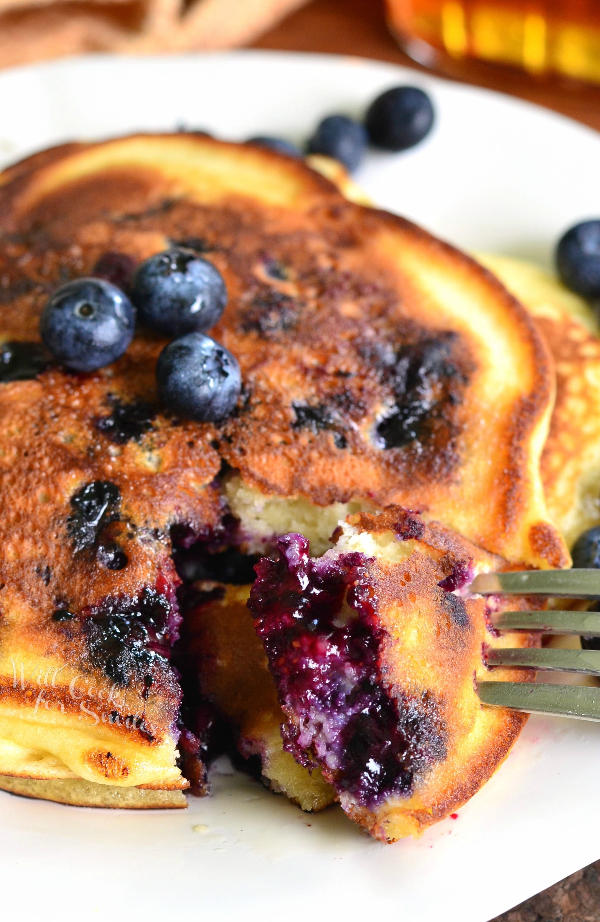 cutting into a blueberry pancake with a fork