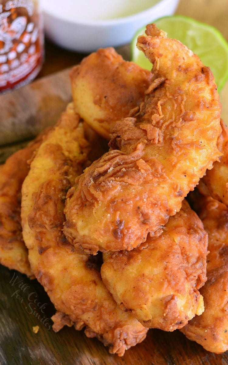 Sriracha Crispy Chicken Tenders stacked on a cutting board 