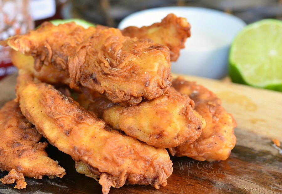 Chicken Tenders stacked up on a cutting board 