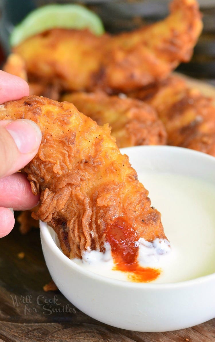 Dipping Sriracha Crispy Chicken Tenders in Honey Dipping Sauce 