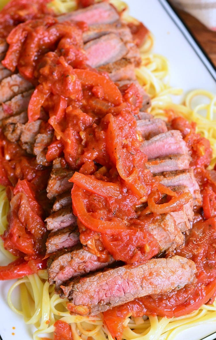 Steak Pizzaiola Linguine on a plate with onion and tomato sauce on top 