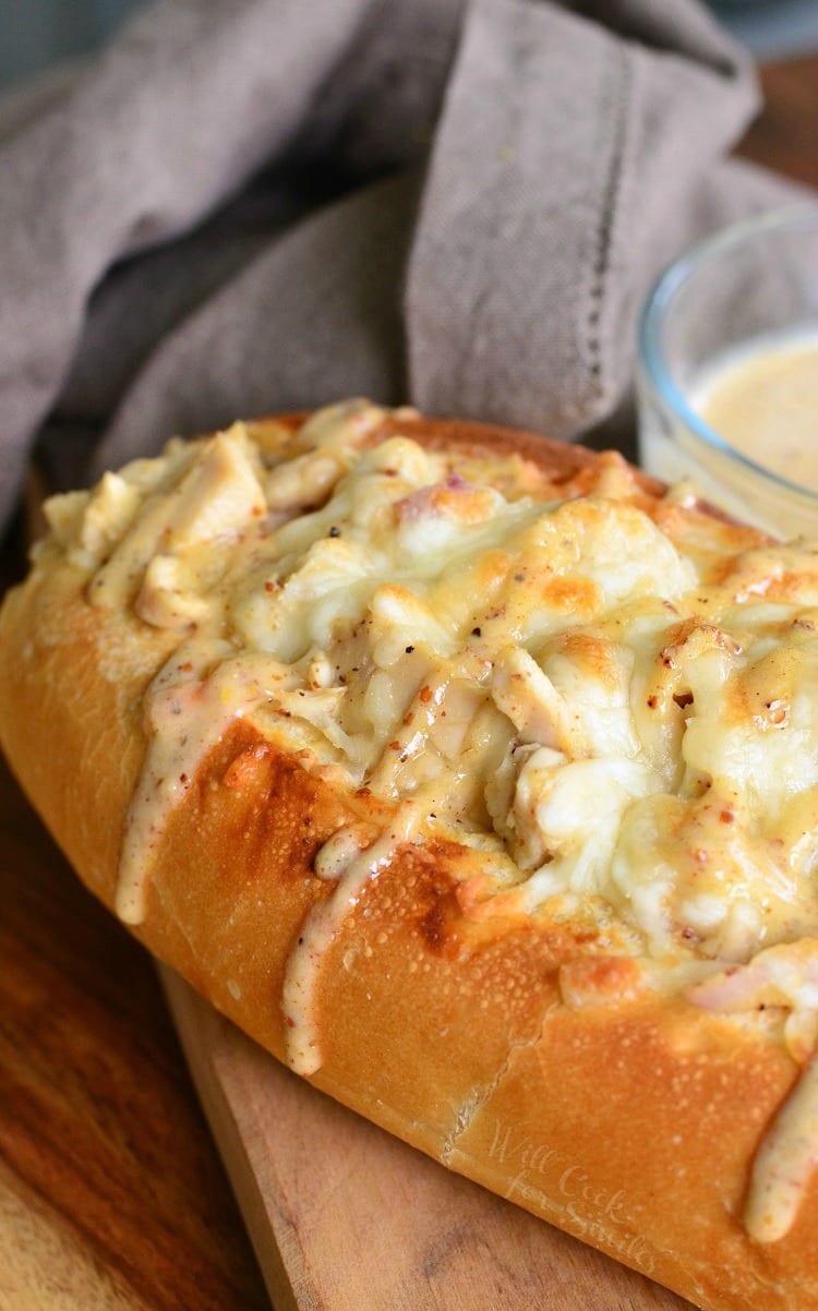 Chicken Sub with white bbq on top on a cutting board with a bowl of white bbq sauce in the background to the right