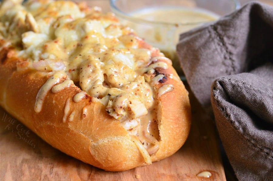 Chicken Sub with white bbq on top on a cutting board with a bowl of white bbq sauce in the background to the right