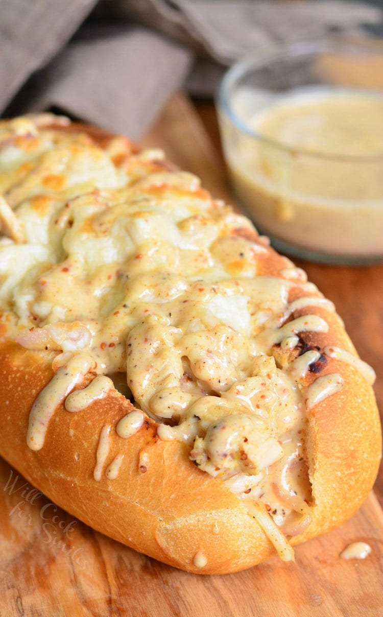 Chicken Sub with white bbq on top on a cutting board with a bowl of white bbq sauce in the background to the right