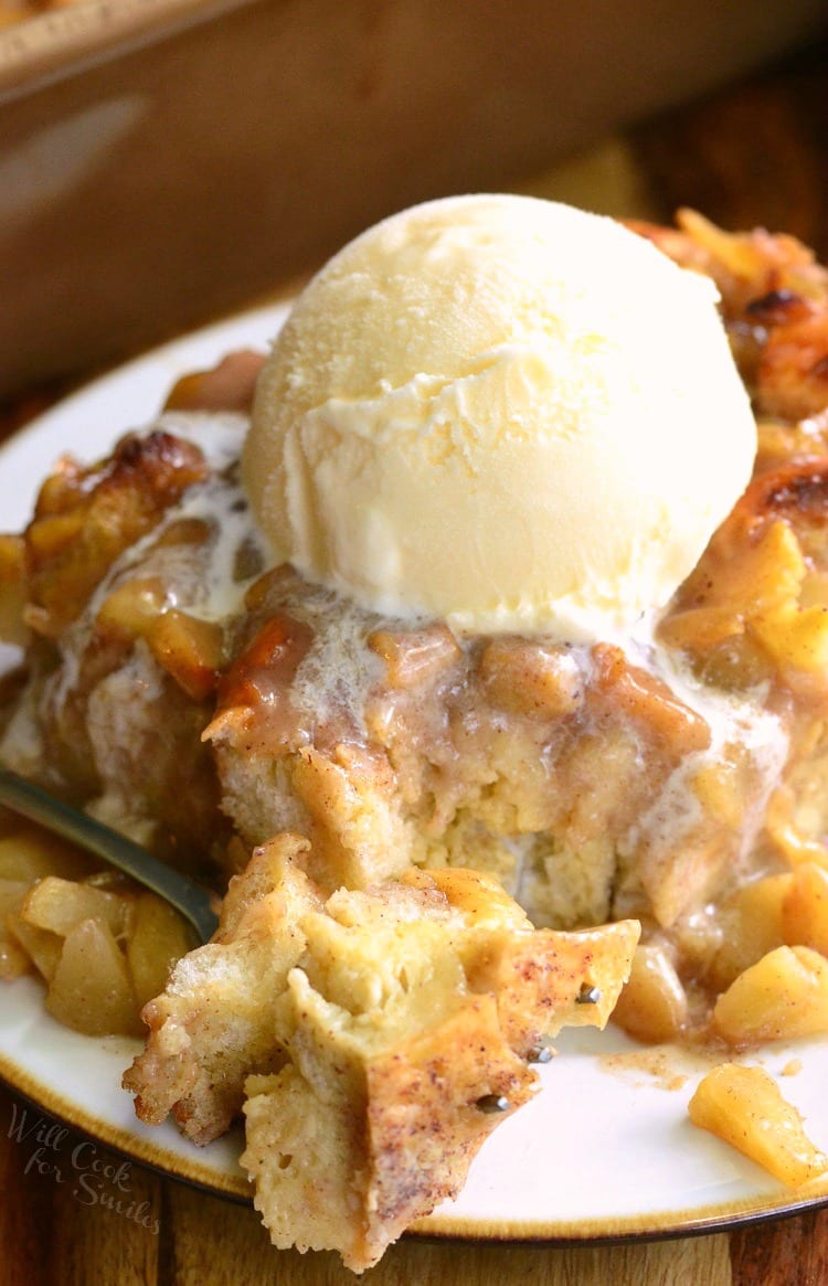 Apple Pie Bread Pudding with a scoop of vanilla ice cream on top with a scoop on a fork to the left 