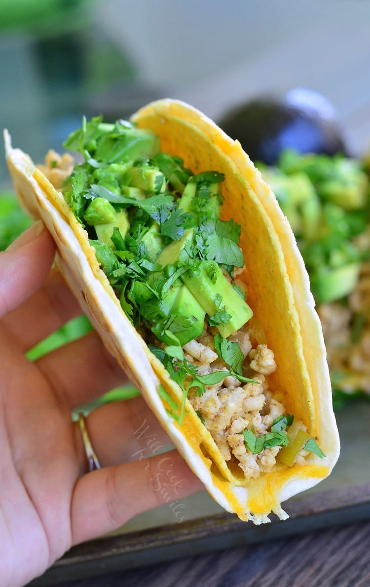 holding Avocado Turkey Tacos in a hard shell with ground turkey, avocado and cilantro 