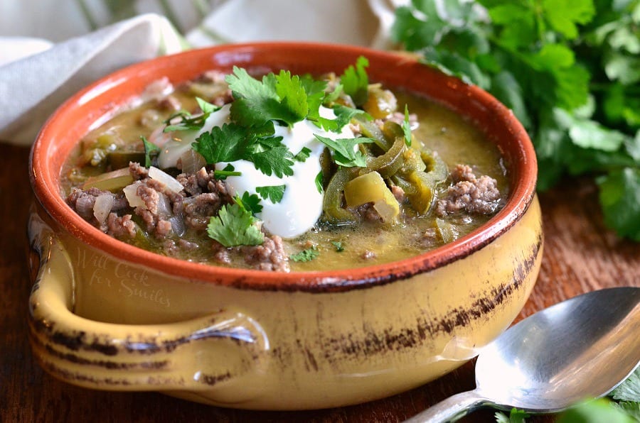 horizonal view ground Beef and Poblano Enchilada Soup. hamburger with poblano peppers in a soup bowl with sour cream and cilantro on top 