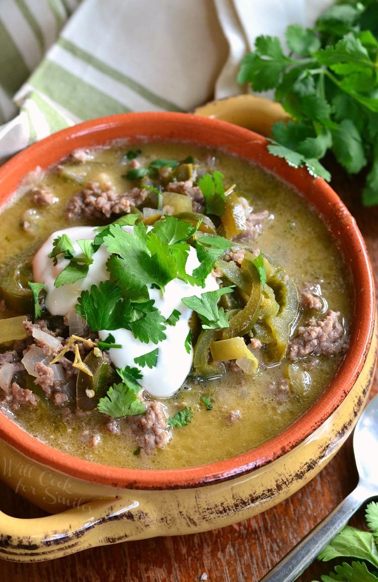 top view of Beef and Poblano Enchilada Soup ground beef with poblano peppers in a soup bowl with sour cream and cilantro on top 