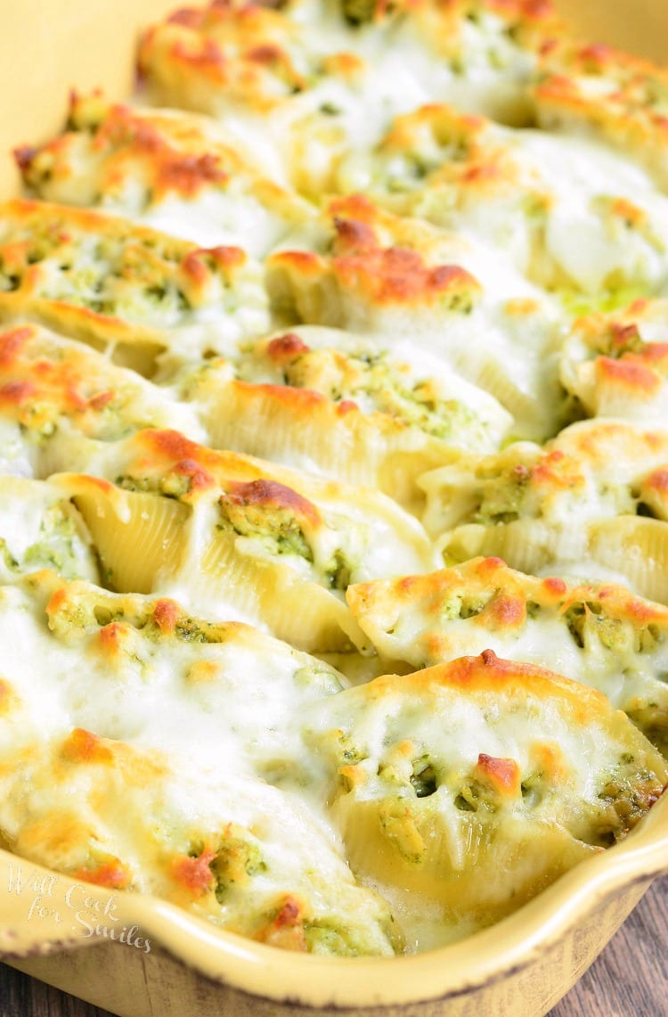  Cheesy Pesto Chicken Stuffed Shells with cheese melted on top in a yellow baking dish 