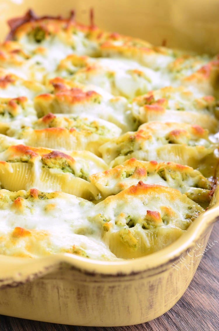 Cheesy Pesto Chicken Stuffed Shells with cheese melted on top in a yellow baking dish 