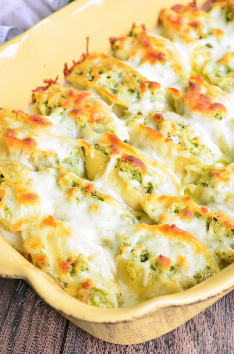 top view of Cheesy Pesto Chicken Stuffed Shells with cheese melted on top in a yellow baking dish 