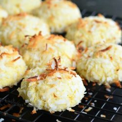 Coconut pudding cookies on a wire rack resting on a black table.