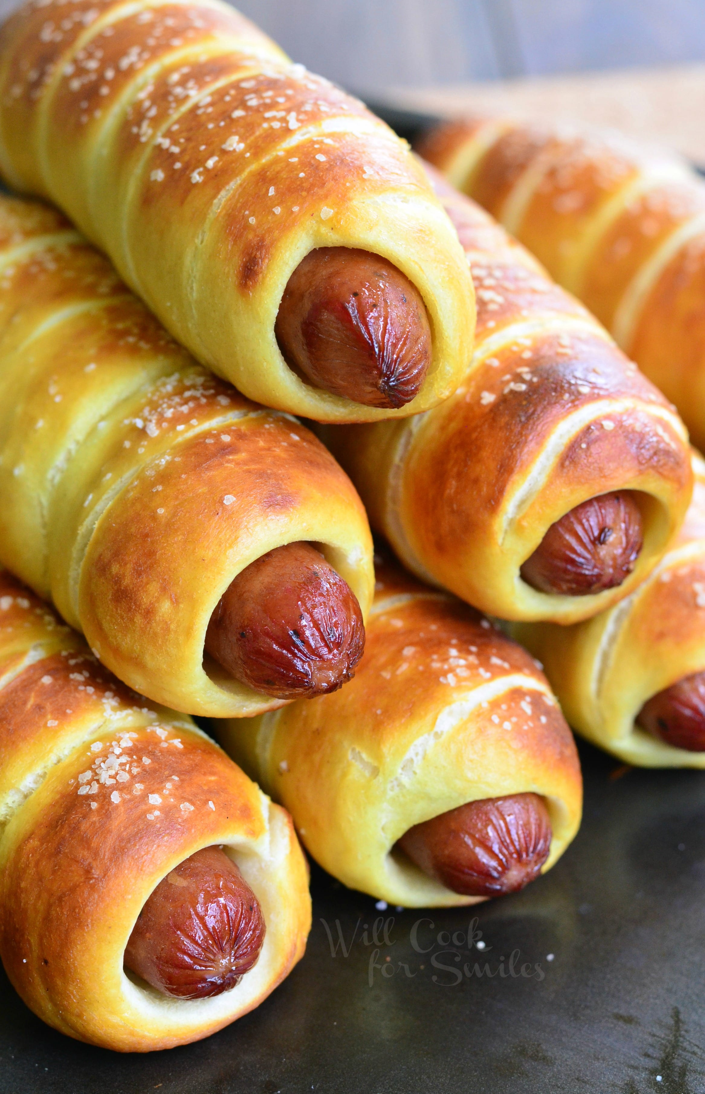 close up of Pretzel Wrapped Hot Dogs stacked up on baking sheet 