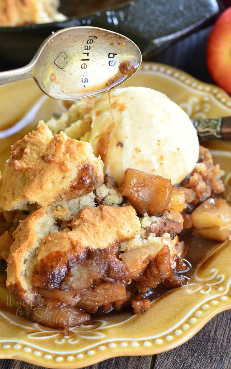 Maple Pecan Apple Cobbler Skillet with a scoop of vanilla ice cream with a spoon above it that says be fearless on a yellow plate 