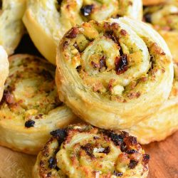 stack of chicken and sun dried tomato pinwheels on a wooden cutting board as seen from above.