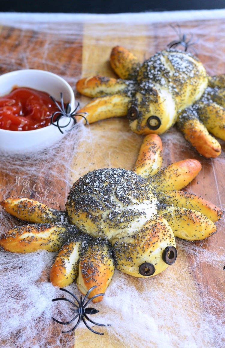 Pretzel Spiders with black olive eyes and red dipping sauce in white bowl with fake plastic spiders 