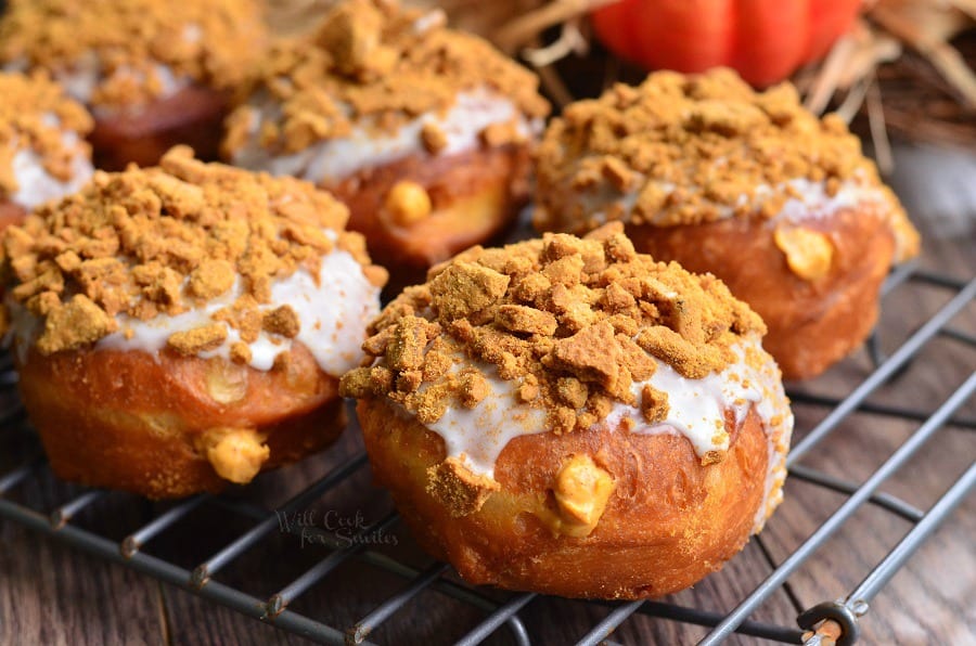 Pumpkin Cheesecake Doughnuts with Gingersnap on top on a cooling rack 