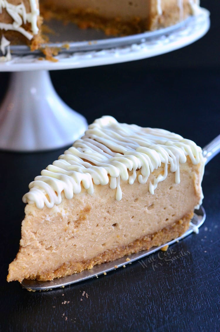 Slice of cheesecake on a pie server with white frosting over top 