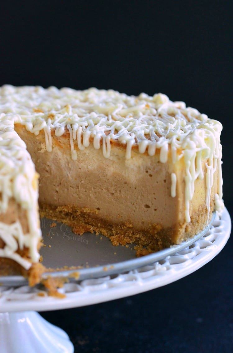 White Chocolate Peanut Butter Cheesecake with slice missing on a cake stand 