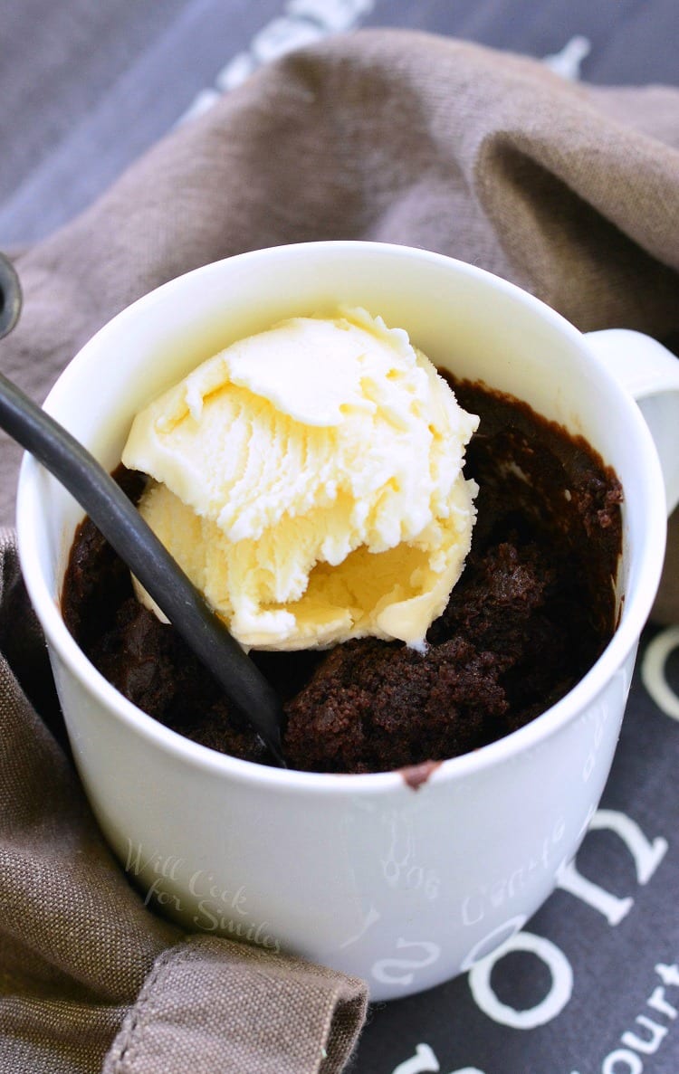 top view of Chocolate cake and vanilla ice cream in a white coffee mug with a spoon lifting some out 