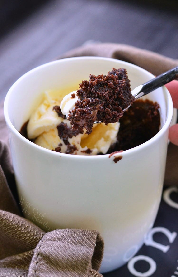 Chocolate cake and vanilla ice cream in a white coffee mug with a spoon lifting some out 