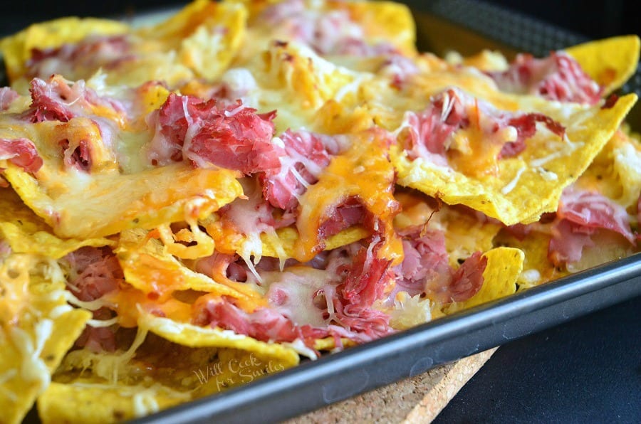 horizonal photo of Tortilla chips, corn beef, and cheese on a baking sheet 