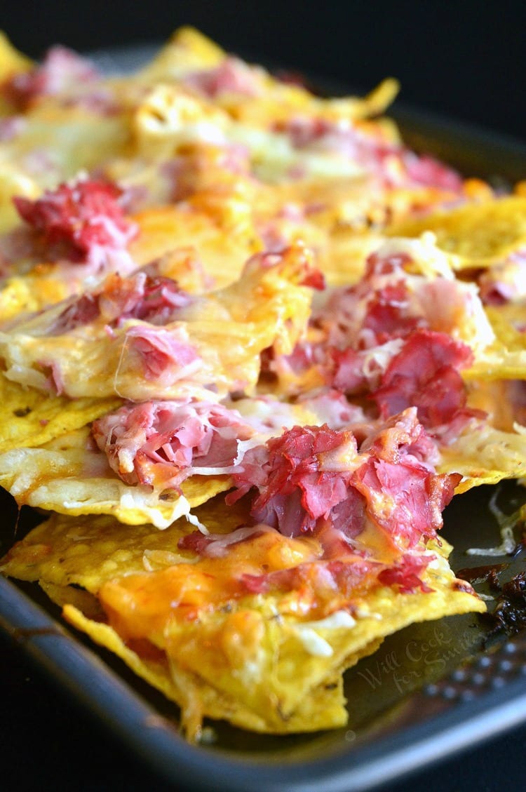 Tortilla chips, corn beef, and cheese on a baking sheet 