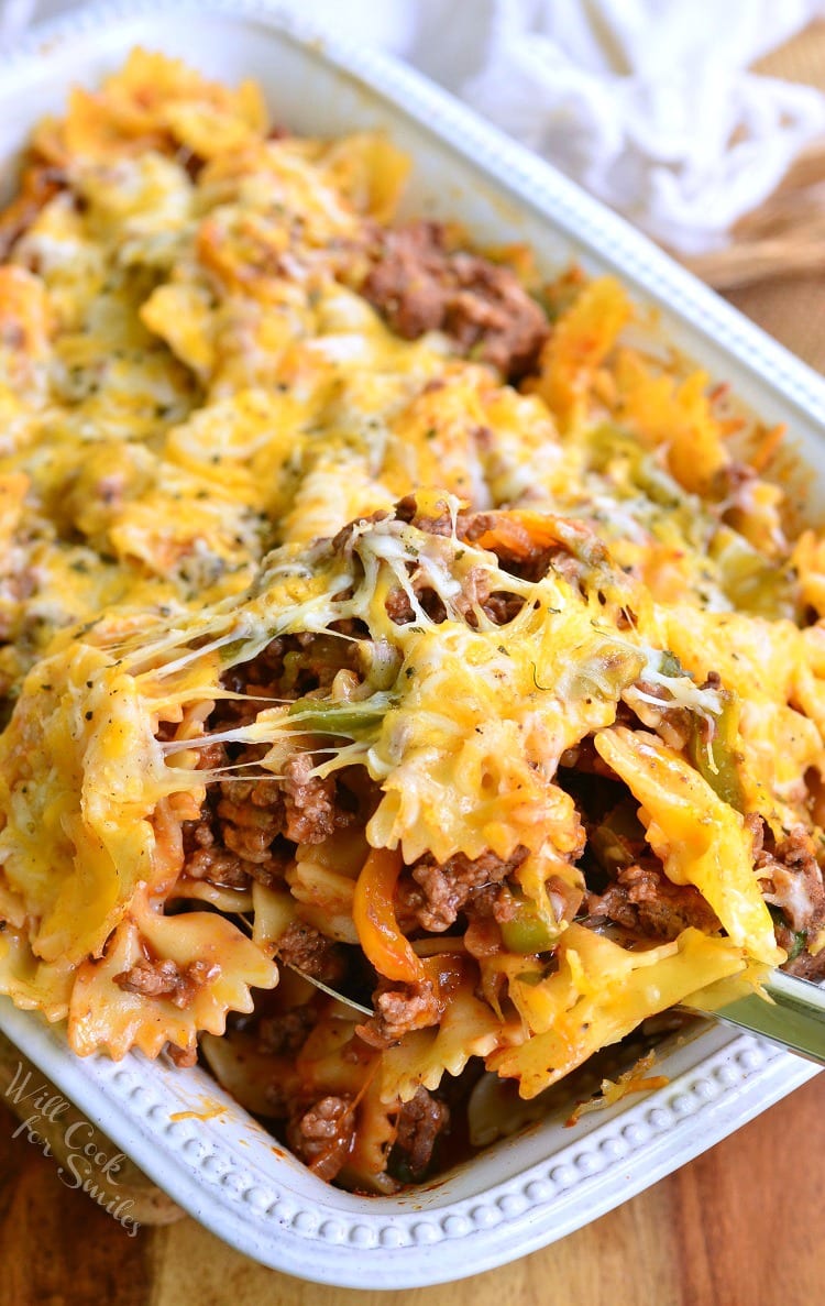 Scooping Stuffed Peppers Pasta Casserole out with a serving spoon in a white casserole dish 