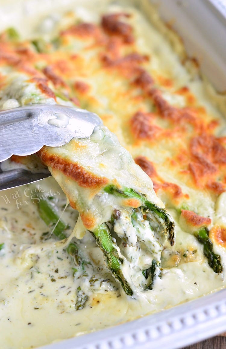 pulling out some baked asparagus with tongs.