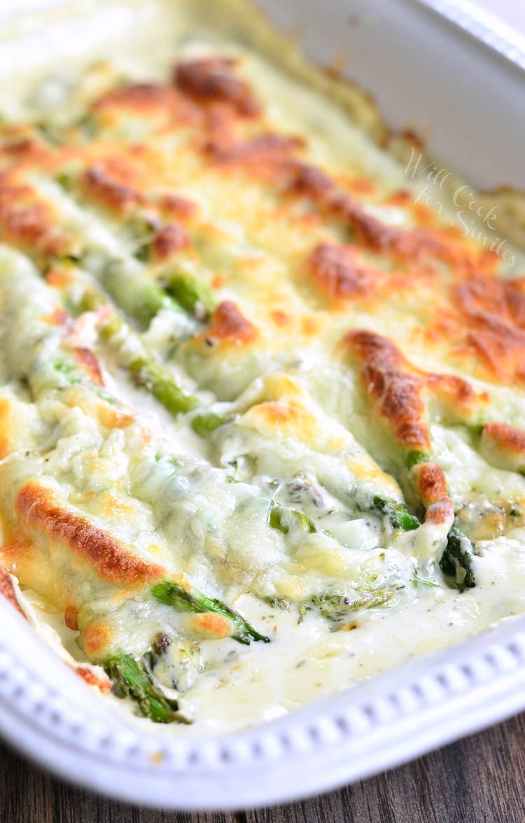 closeup of creamy baked asparagus in a white dish.