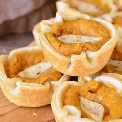 8 mini pumpkin cheesecake pie on a wooden table.