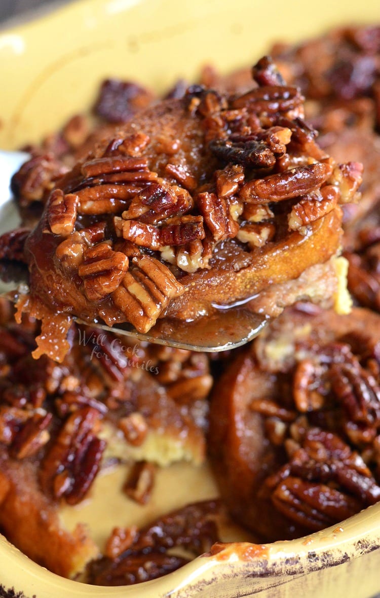 Pecan Pie French Toast Casserole in a yellow casserole dish being lifted out with a spatula 