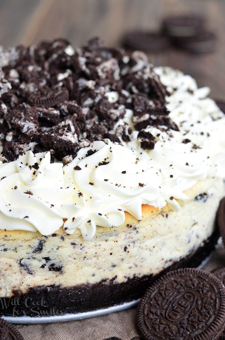 Oreo cheesecake on a table with oreo cookies to the right 