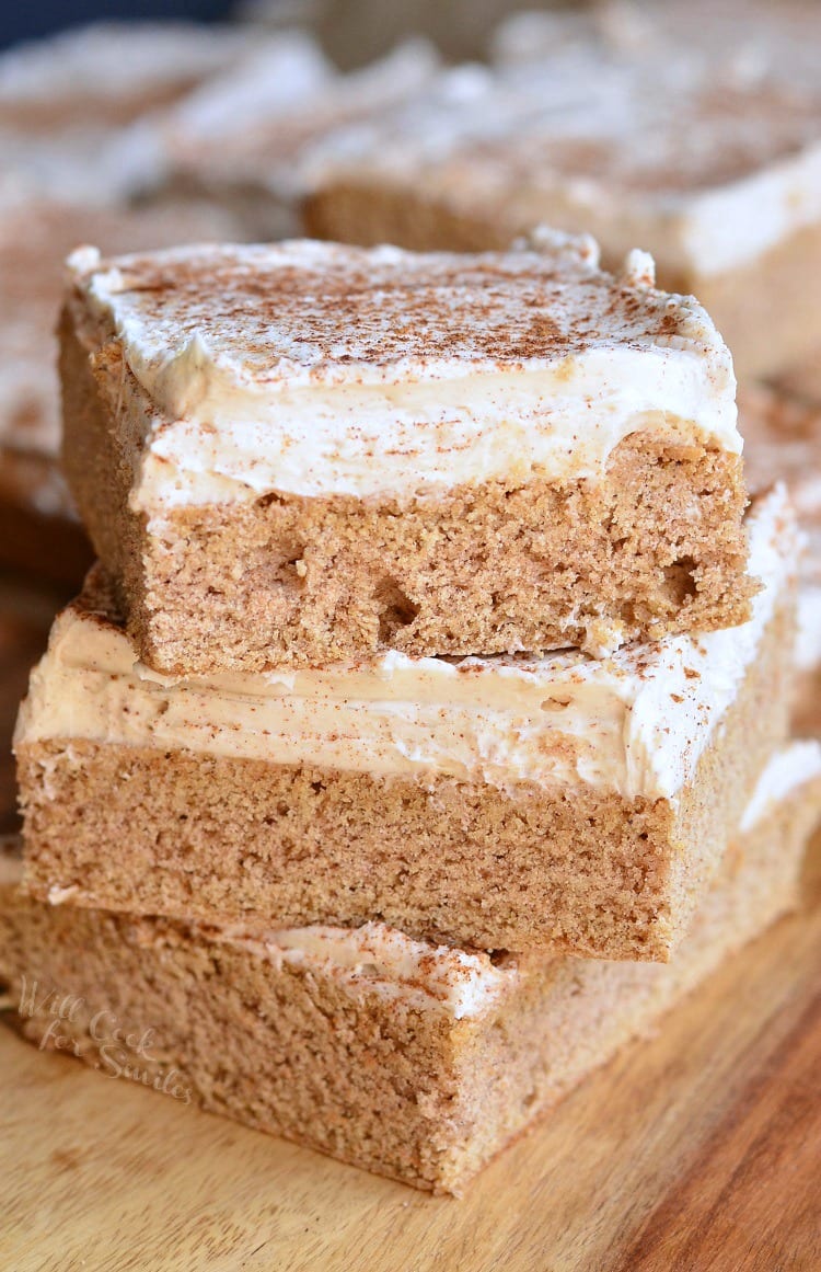 Cinnamon Brown Butter Sugar Cookie Bars with frosting on stacked up on a cutting board 