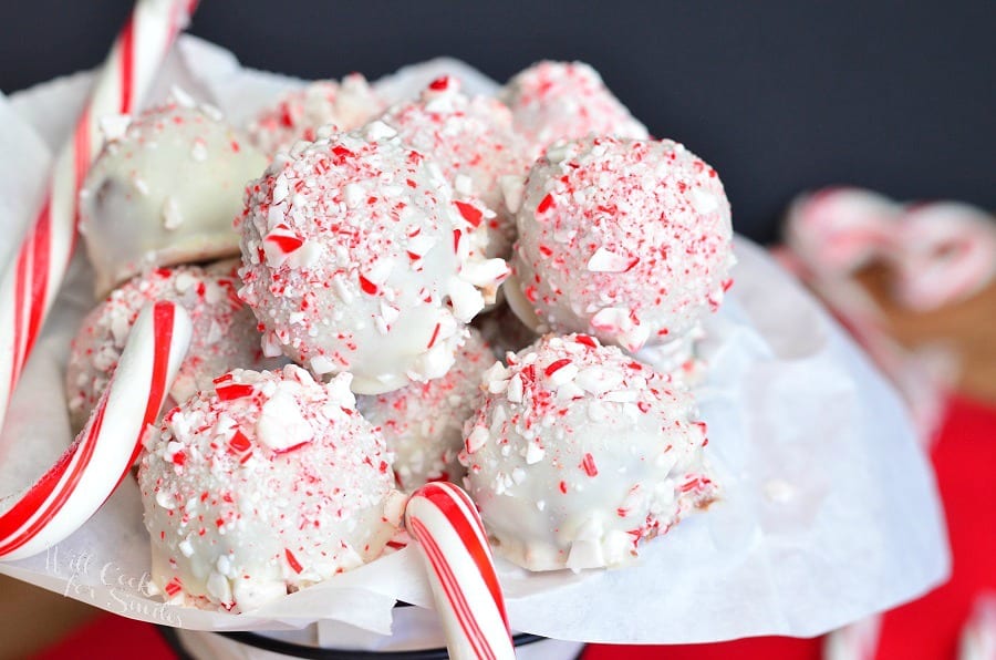 horizontal image of little round chocolate truffles coated in crushed peppermint with candy canes in a white tissue