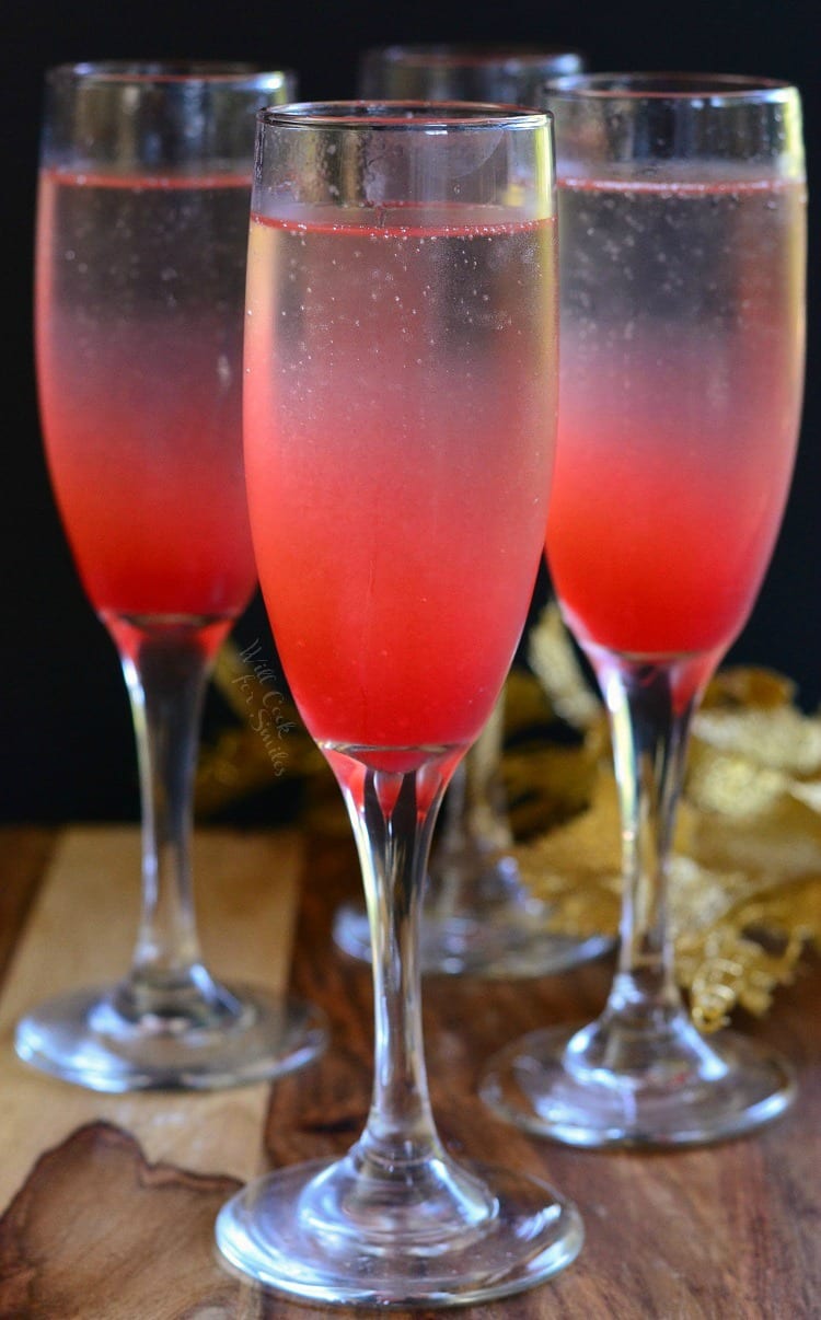 3 Raspberry Italian Soda Champagne Cocktail in a champagne flute on a table 