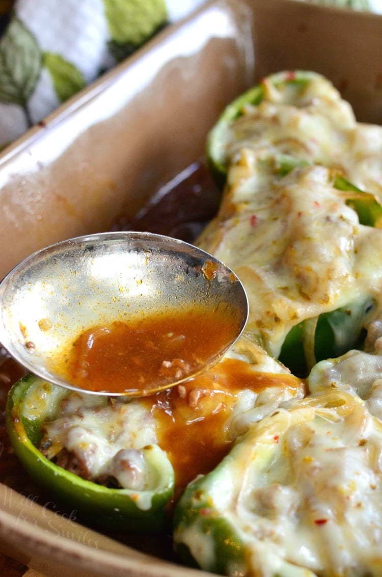 pouring some sauce over the cheesy stuffed bell pepper half. 