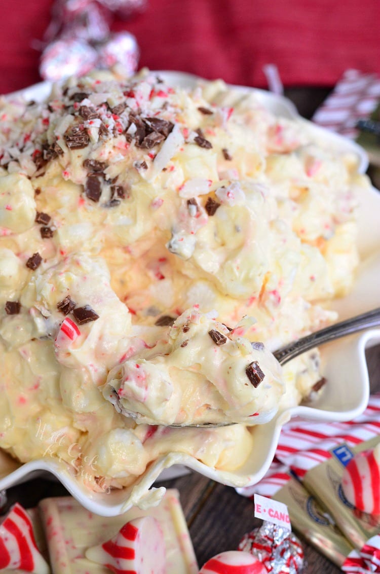 White Chocolate Peppermint Fluff Salad in a white bowl spooning some out with a metal spoon 