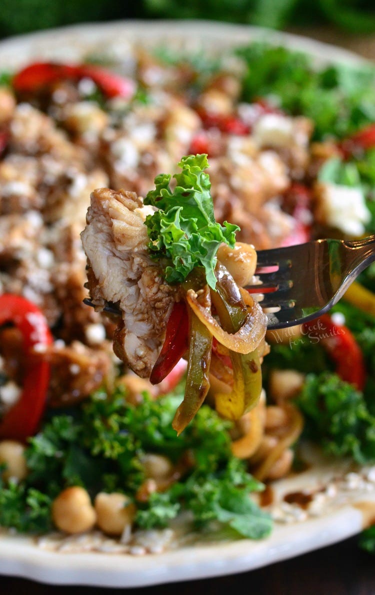 kale salad topped with chicken and veggies that have been sauteed in balsamic on a white plate with a fork dressing, chick peas, and finally, lots of feta cheese on a white plate with some of it on a fork 