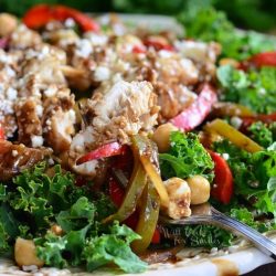 White decorative bowl filled with balsamic chicken, veggies and chick pea salad as viewed close up.