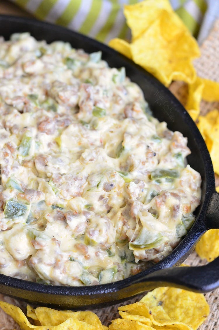 Cheesy Sausage Peppers and Onions Dip in a cast iron pan with chips around it 